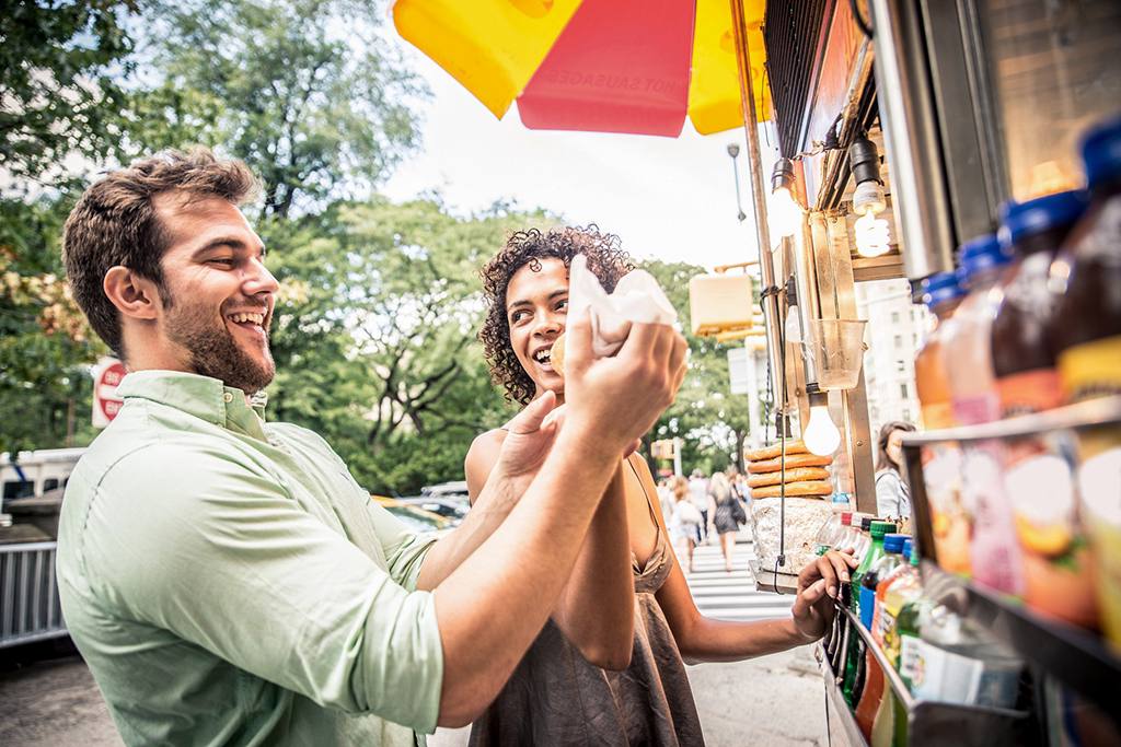 Two people enjoying a meal at a food truck festival.