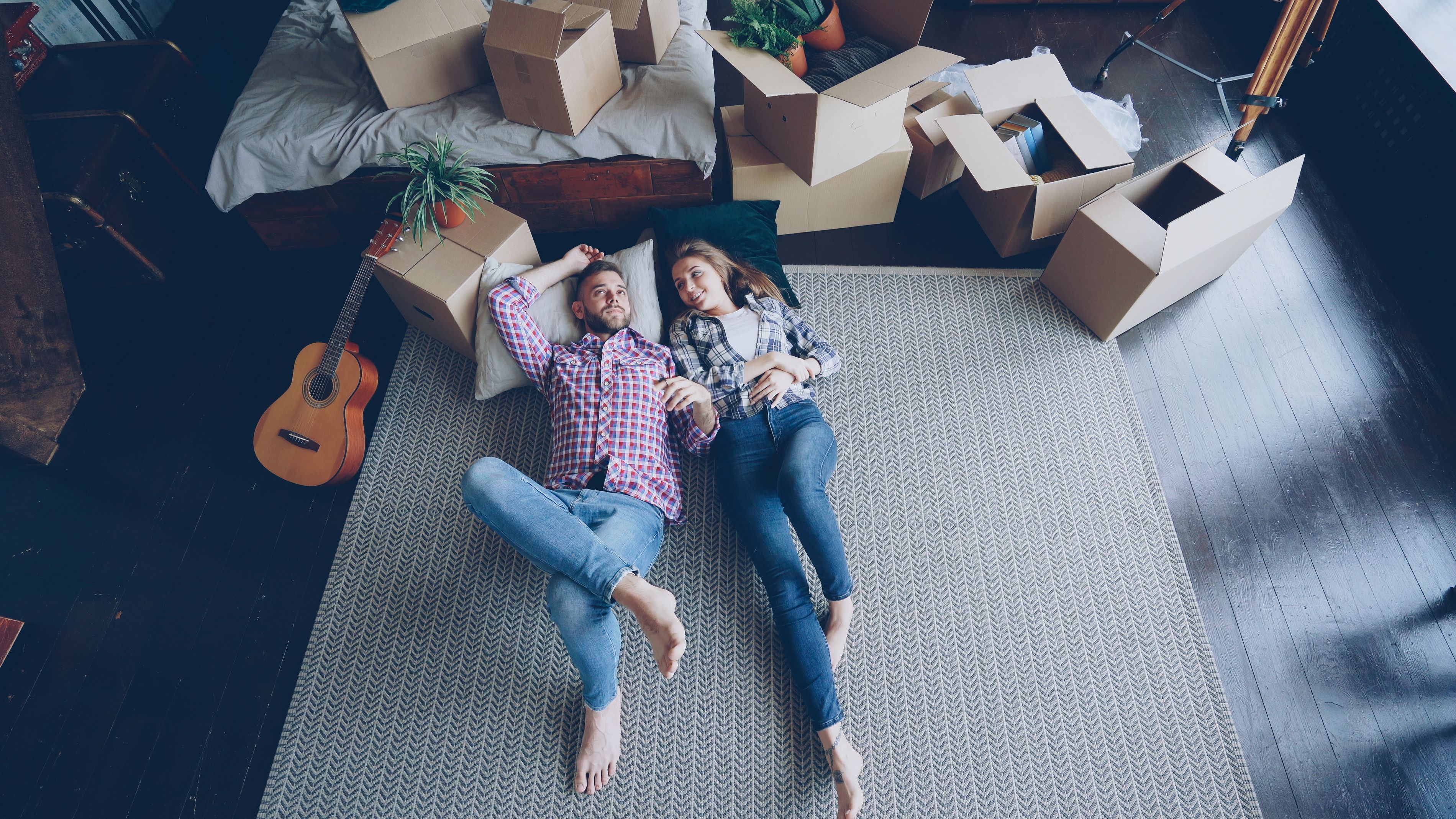 Couple resting on the floor of their new home among moving boxes