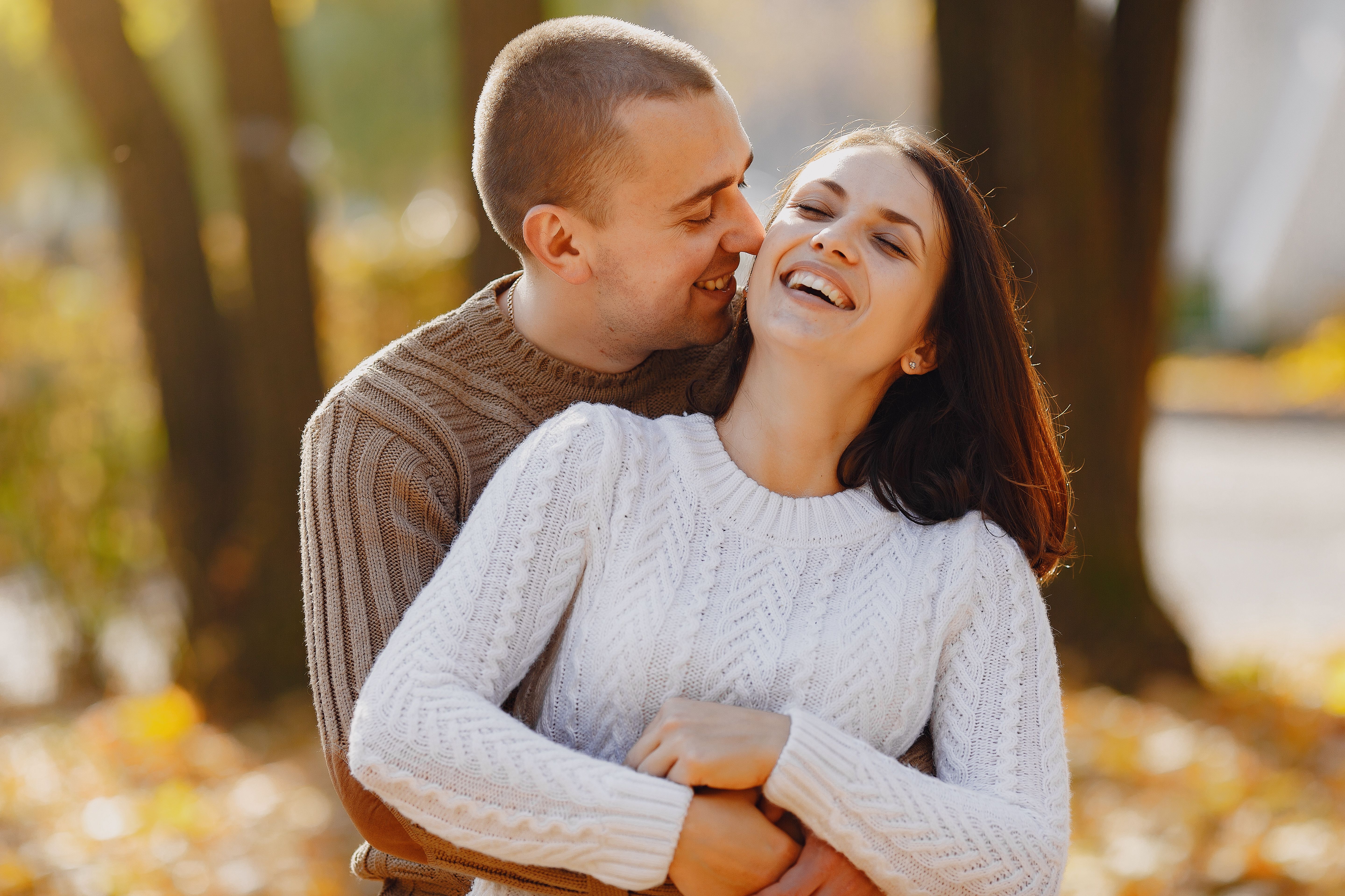 Happy couple in cozy sweaters hugging outdoors, reflecting the warmth of finding love with Step2Love.